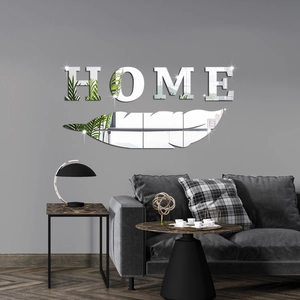 Close-up of modern HOME letter mirror stickers and feather wall decor on grey wall
