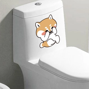 Detail showing a cute Shiba Inu cartoon sticker on a white bathroom toilet seat cover