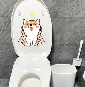 Detail showing a cute Shiba Inu cartoon sticker applied on a white toilet lid surface