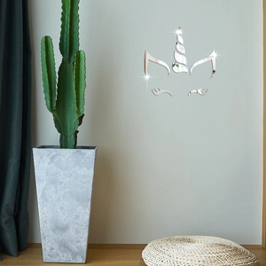 Detail of DIY mirror wall stickers showing silver unicorn horn and eyelashes on gray wall
