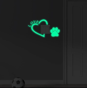 Glow in the dark wall stickers showing luminous green heart and paw prints near a light switch
