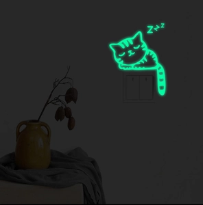 Glow in the dark sleeping cat wall sticker illuminating a dark room with green neon light