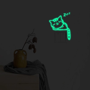 Glow-in-the-dark cat wall sticker on a light switch showing bright green fluorescence