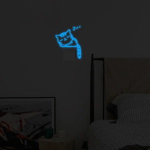 Blue glow-in-the-dark cat sticker glowing above a wall switch in a dark bedroom