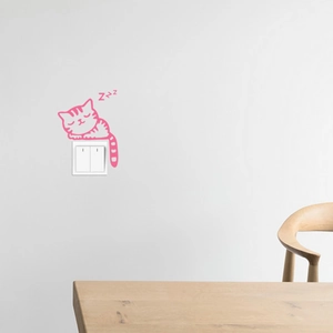 Detailed view of pink cartoon cat wall sticker sleeping above a white light switch