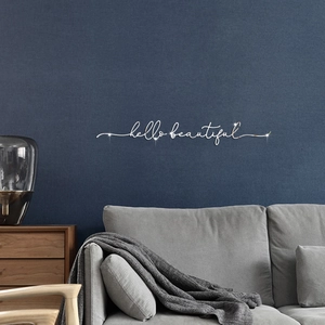 Close-up of Hello Beautiful mirrored acrylic wall sticker in cursive font on a blue wall