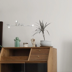 Close-up of silver mirror arrow love wall sticker decoration in a modern bedroom