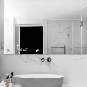 Macro detail of silver mirror LOVE acrylic wall sticker on modern bathroom tile surface
