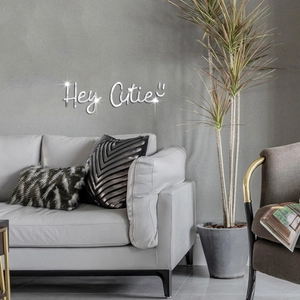 Silver acrylic mirror wall sticker with Hey Cutie text above a modern living room sofa