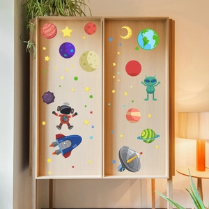 Space themed wall stickers with planets and astronauts on light wood cabinet surface
