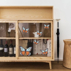 Detailed view of self-adhesive butterfly wall stickers on glass furniture in a bedroom