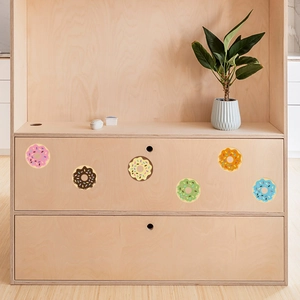 Detailed view of six colorful glowing donut wall stickers on a light wooden cabinet drawer