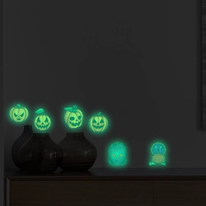 Close-up of six glowing pumpkin wall stickers on a dark wall for Halloween decor