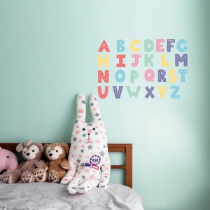 Détail des stickers muraux alphabet A-Z colorés sur un mur bleu dans une chambre d'enfant