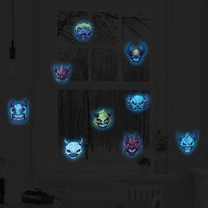 Set of 9 luminous Halloween monster stickers glowing in the dark on a night window