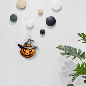 Close-up of a wooden Halloween pumpkin charm with a purple witch hat hanging on a wall