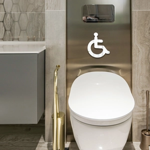 Macro detail of white acrylic disability access sign on a modern bathroom metal panel