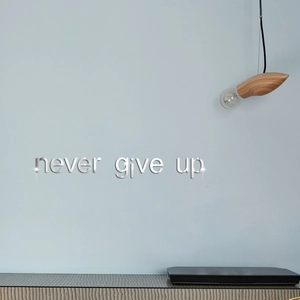 Detail of 3D silver mirror wall sticker showing 'never give up' quote in a modern room