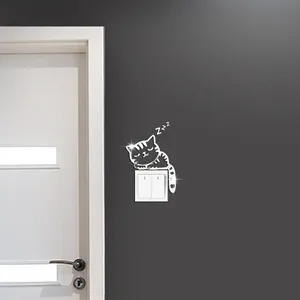 Détail d'un sticker mural chat en acrylique au-dessus d'un interrupteur blanc sur mur gris