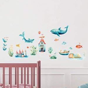 Nursery wall with watercolor ocean fish and whale stickers above a pink crib