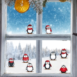 Acht Weihnachts-Pinguin-Wandtattoos mit roten Mützen auf einer frostigen Fensterscheibe