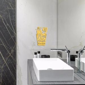 Detail view of golden acrylic toothbrush wall decal with Floss and Brush lettering