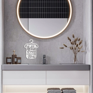 Detail of Hello Sweet Cheeks baby onesie sign on a gray stone bathroom wall with a backlit mirror