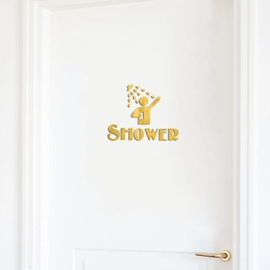 Close-up of golden acrylic shower mirror sticker with human icon and text on a white door