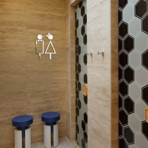 Detailed view of silver mirror acrylic restroom signs on a beige stone textured wall