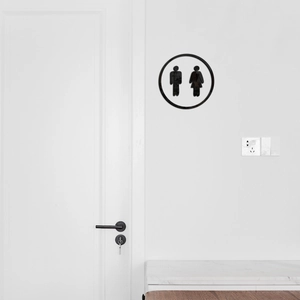 Minimalist black round acrylic restroom sign with male and female icons on white wall