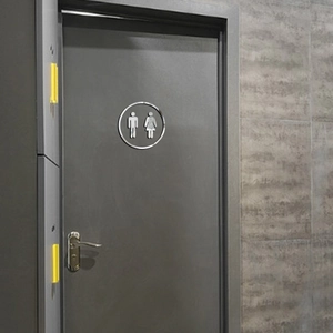 Modern silver mirror acrylic restroom sign with male and female icons on grey door surface