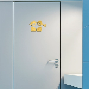 Close-up of golden acrylic mirror restroom signs on a grey door with reflective finish