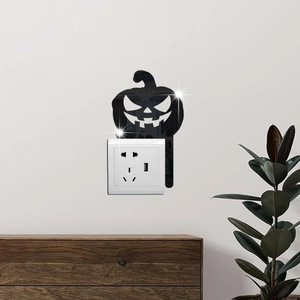 Macro shot of black mirror acrylic pumpkin frame sticker around light switch on a beige wall