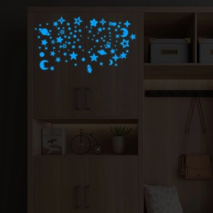 Luminous blue moon and stars wall decals glowing on a dark wardrobe in a bedroom