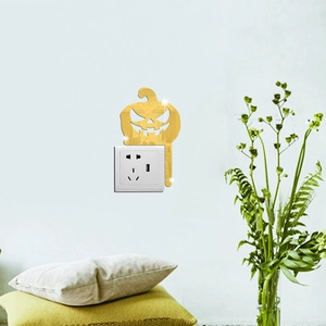 Close-up of golden mirror acrylic pumpkin sticker around a wall switch for Halloween decor