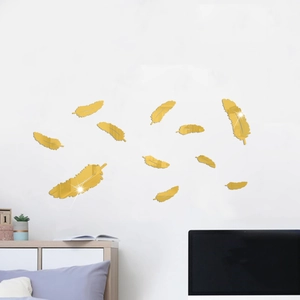 Detailed close-up of 3D gold feather mirror wall stickers on a clean white living room wall