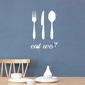 Close-up of silver mirror acrylic cutlery silhouettes and eat well sign on dining room wall