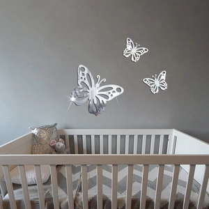 Detailed view of silver hollow 3D butterfly mirror wall stickers on a grey bedroom wall