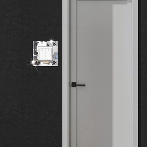 Detail of mirror acrylic light switch cover with black scrollwork on a modern wall