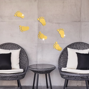Detailed view of six gold mirror acrylic footprint wall stickers on a grey textured wall