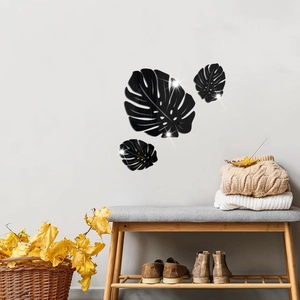 Detail of three black acrylic leaf mirror wall stickers on a minimalist white living room wall