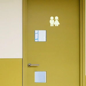 Luminous restroom sign stickers featuring minimalist male and female icons on a wooden door
