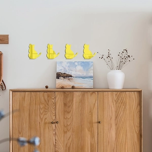 Detailed view of four yellow acrylic cat mirror wall stickers on a light gray bedroom wall