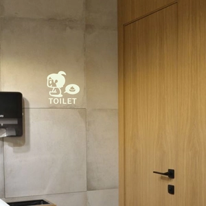 Leuchtender Toilettenaufkleber mit Comic-Mädchen auf grauen Marmorfliesen im Bad