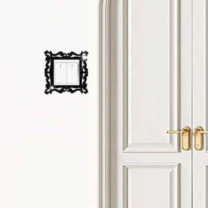 Detail of black acrylic wall switch frame with baroque floral patterns and mirror finish