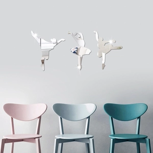 Three silver acrylic ballet dancer wall mirrors displayed above modern chairs on grey wall