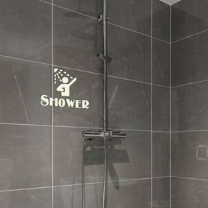 Wall-mounted chrome shower system with mixer valve on dark marble bathroom tiles
