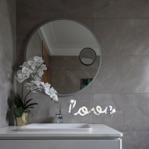 Close-up of mirror finish LOVE wall sticker on marble wall in a modern bathroom