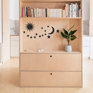 Close-up of black acrylic star and moon mirror wall stickers on light wood bookshelf