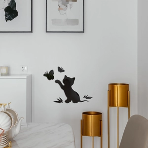 Close-up of black acrylic cat and butterfly wall decals on a clean white interior wall
